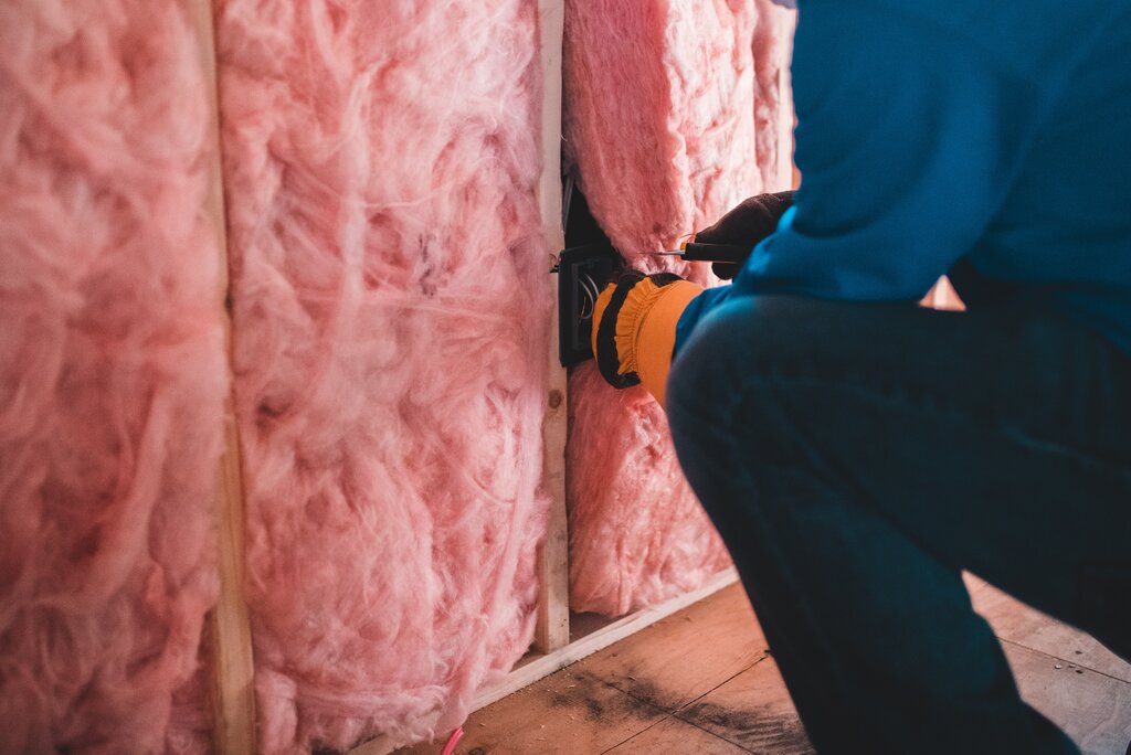 Person installing insulation to a metal carport