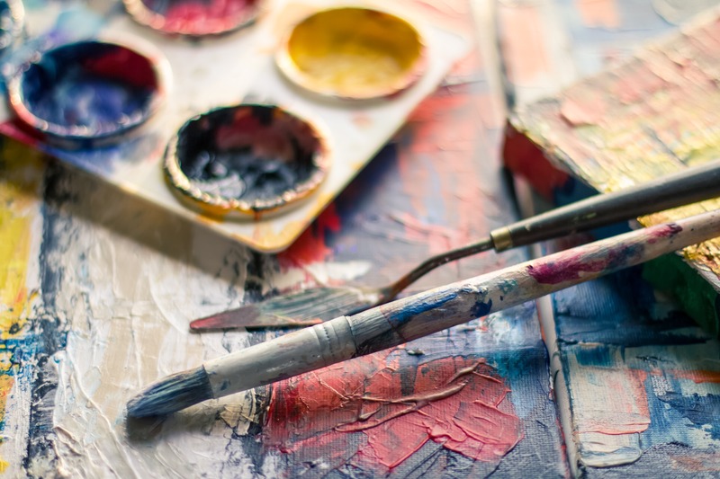Paint and paint brushes on a wooden table: how to build a backyard art studio