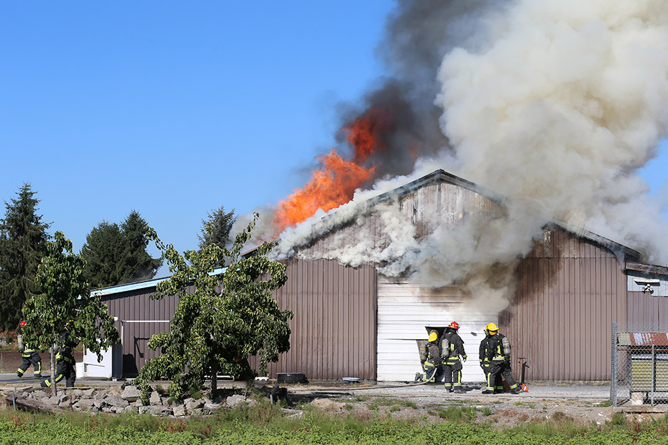 A fire burns inside a metal barn, highlighting the risks of hay storage during summer.
