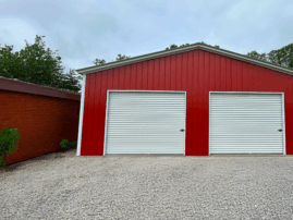 A two-car steel garage in Alvarado, TX, featuring dual white roll-up doors, delivered and installed by American Steel Carports, Inc.